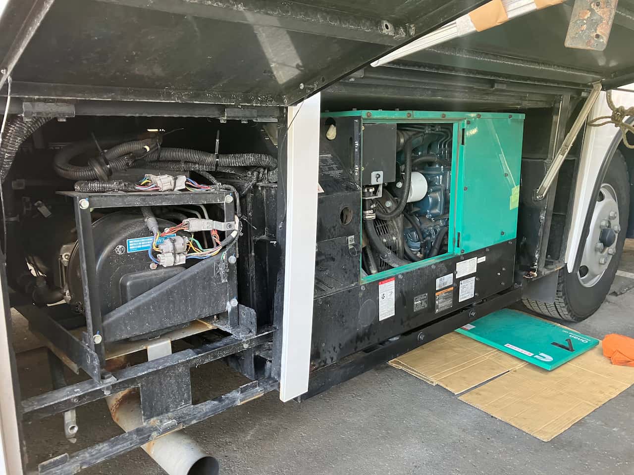 大型車両の側面に搭載された車載発電機（Onan製）のメンテナンスの様子